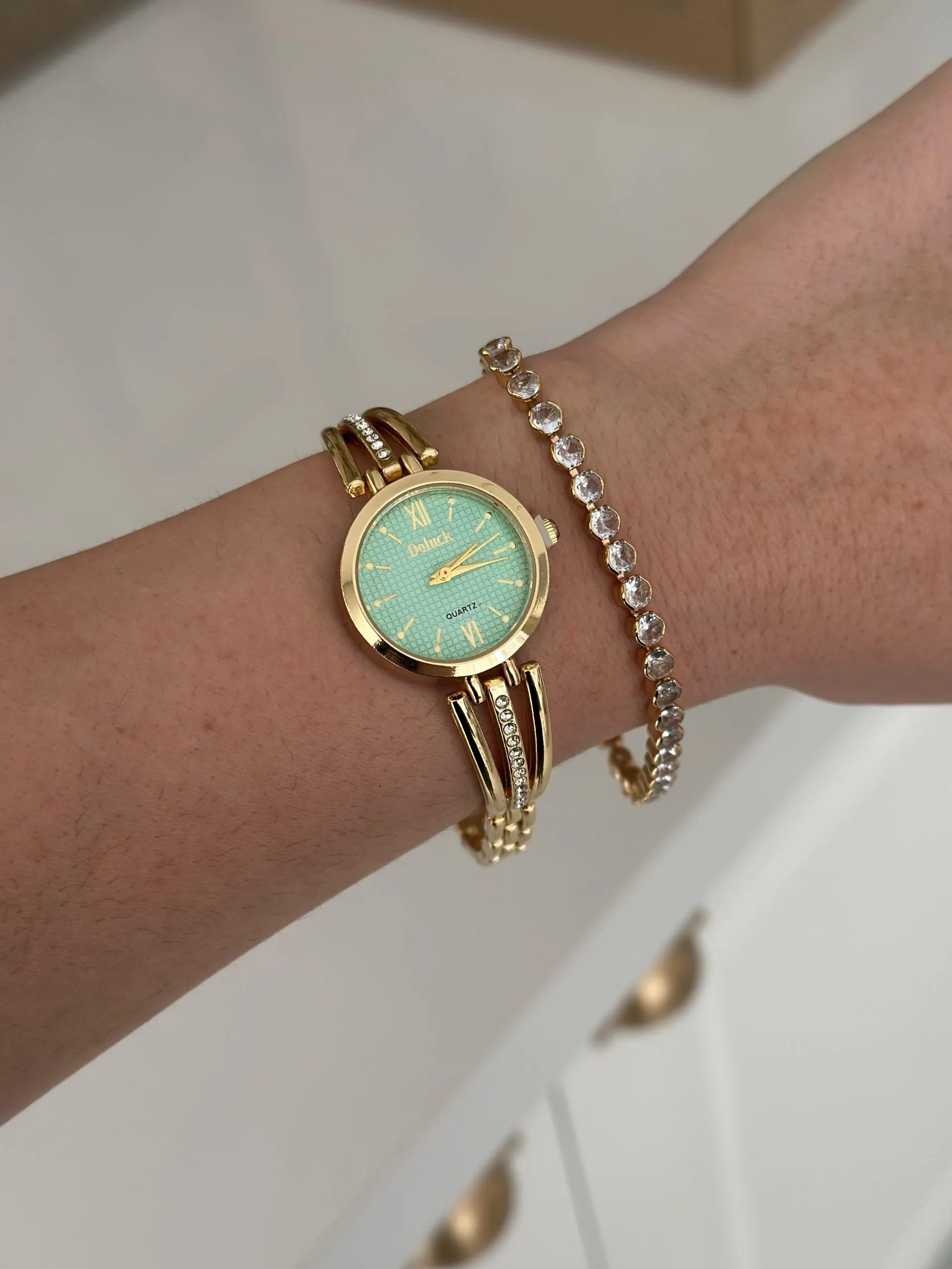 Relógio Dourado Fileira Cravejada com Fundo verde